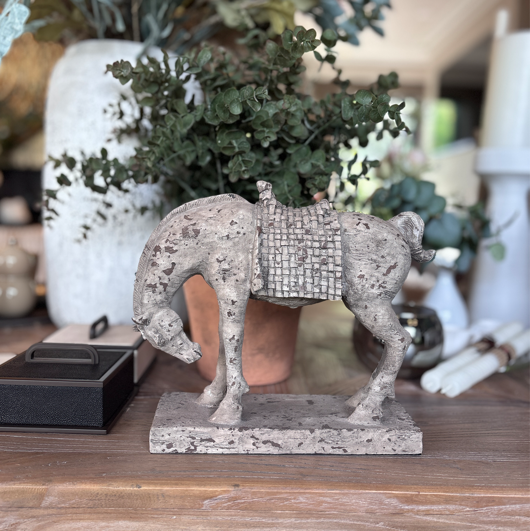 A weathered stone-effect horse figurine in a graceful bowing stance, on a solid rectangular plinth                                     