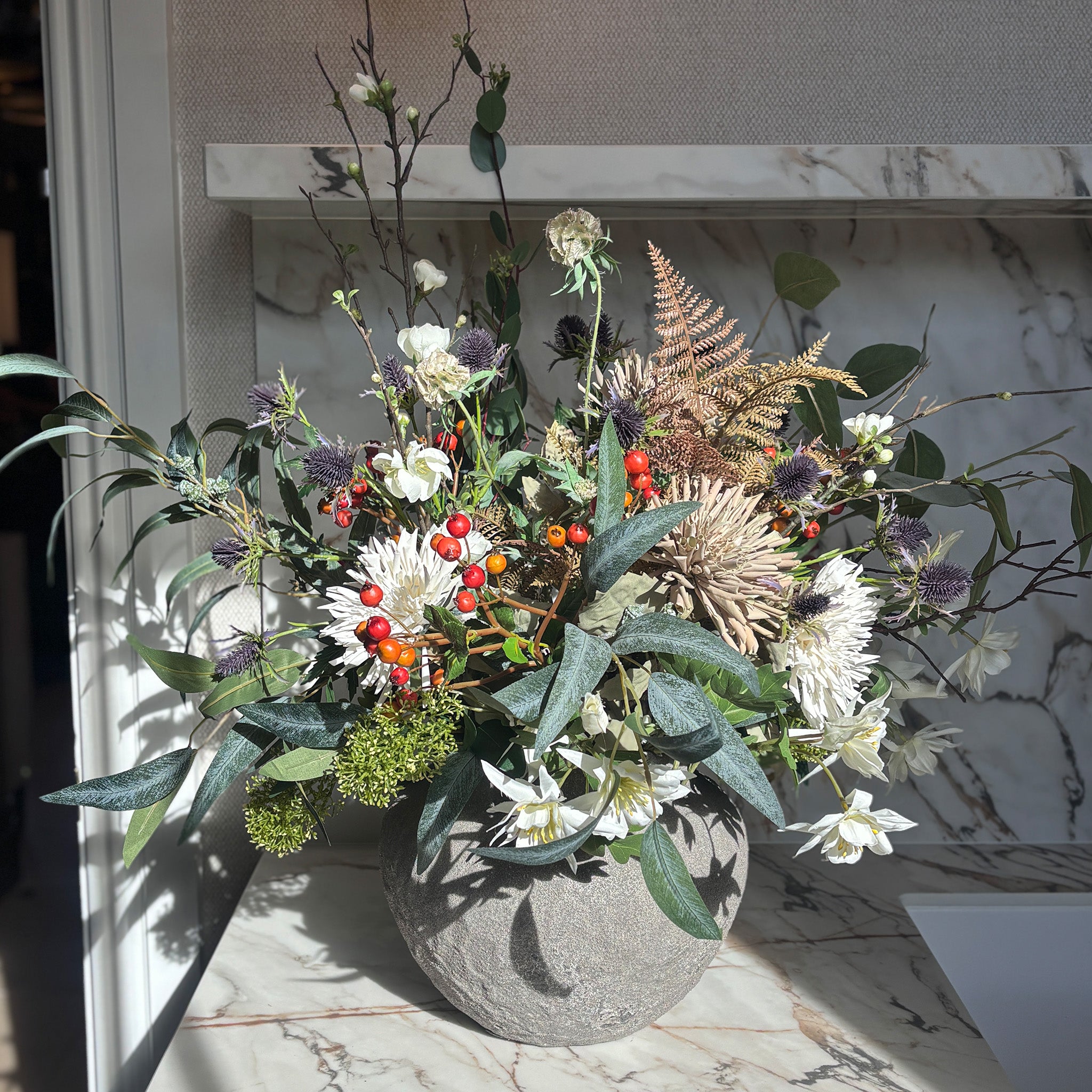 A generous, free-flowing display of thistles and bright rosehip berries, gathered with creamy dahlias, delicate aquilegia and trailing eucalyptus, in our rustic bulbous vase. Overall Height: 80cm, Overall Width: 90cm, Delivery is approximately 2 to 10 working days, depending on stock availability