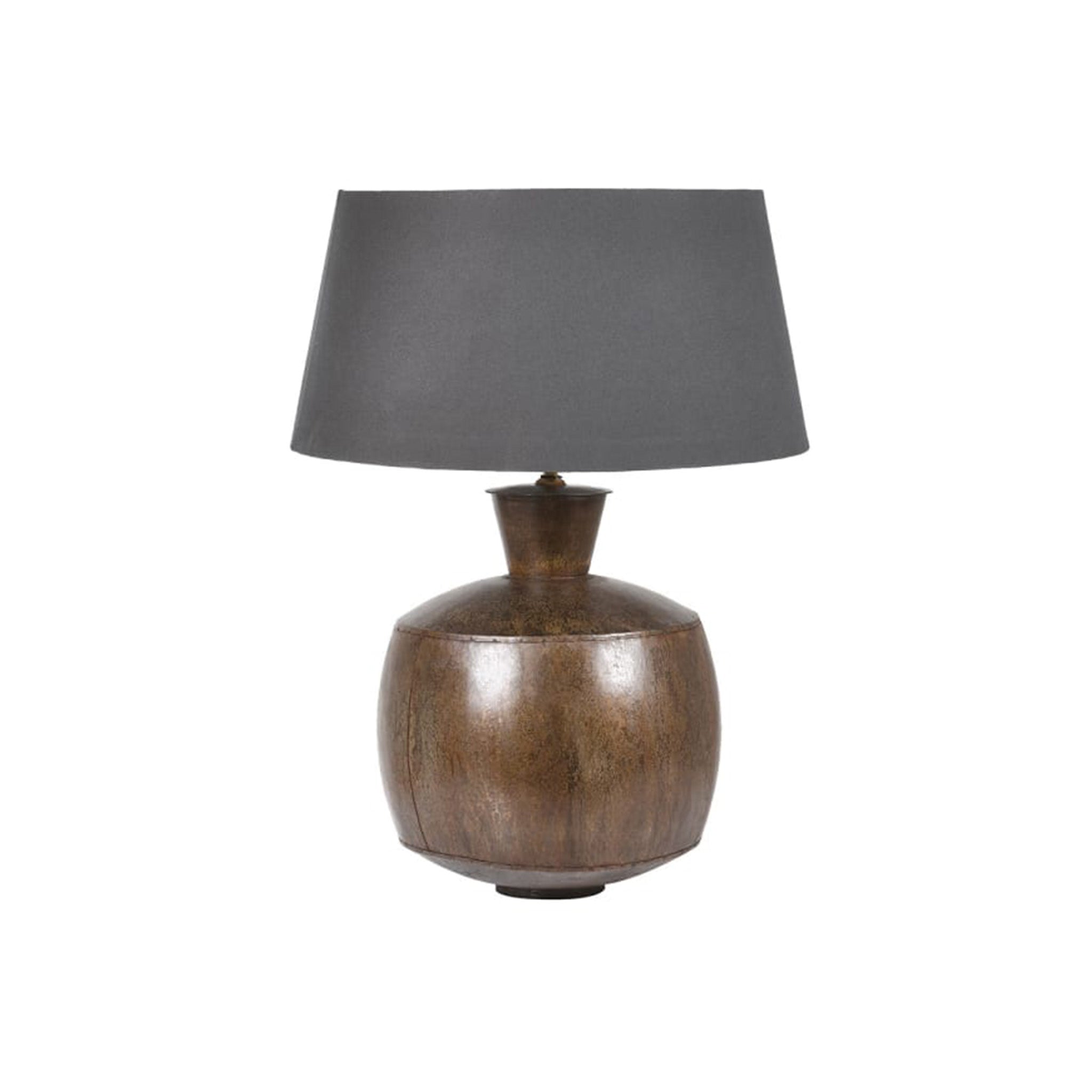 A substantial table lamp with a rounded, bulbous metal base in an antique bronze finish. The aged, patinated surface gives it an artisanal, industrial feel, topped with a tapered grey fabric shade.