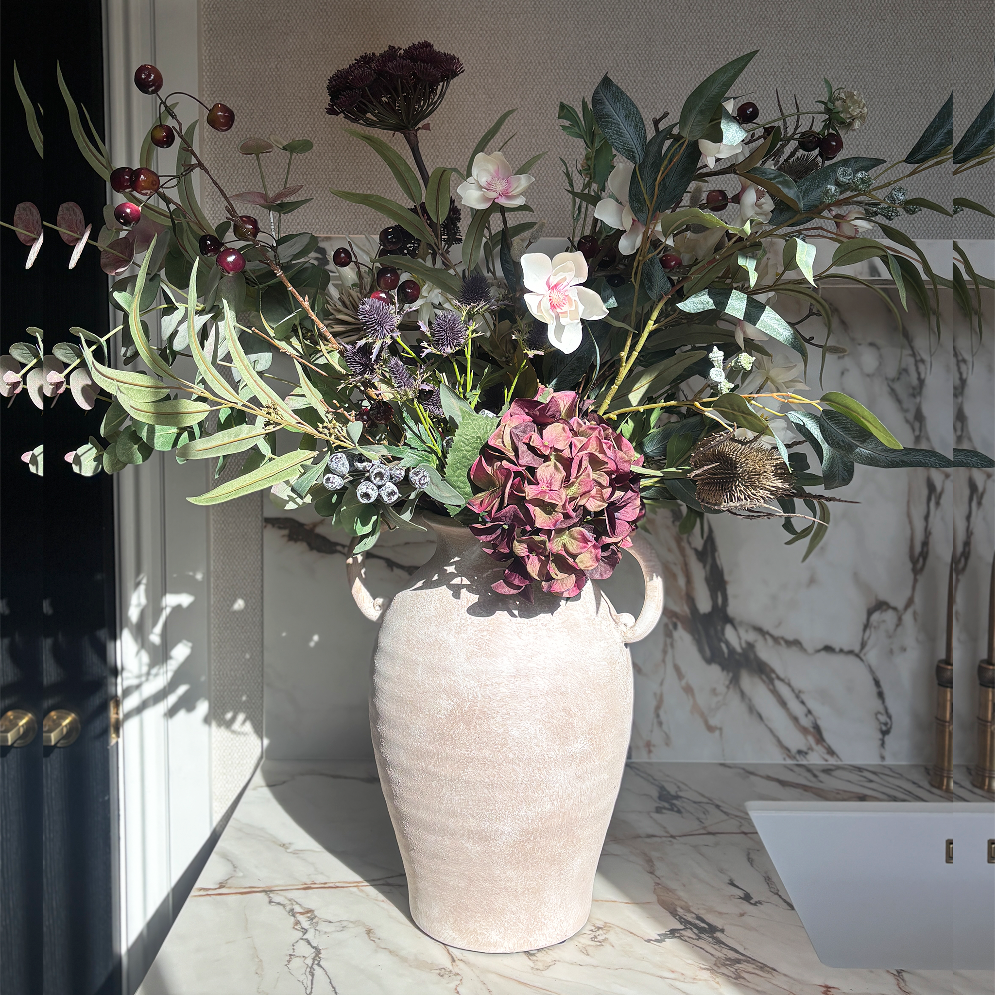An abundant, free-flowing display inspired by a walk through the countryside, centred on plum hydrangeas and gathered with thistles, soft cream magnolias, dark cherries and trailing eucalyptus. Overall Height: 70cm Overall Width: 60cm, Delivery is approximately 2 to 10 working days, depending on stock availability